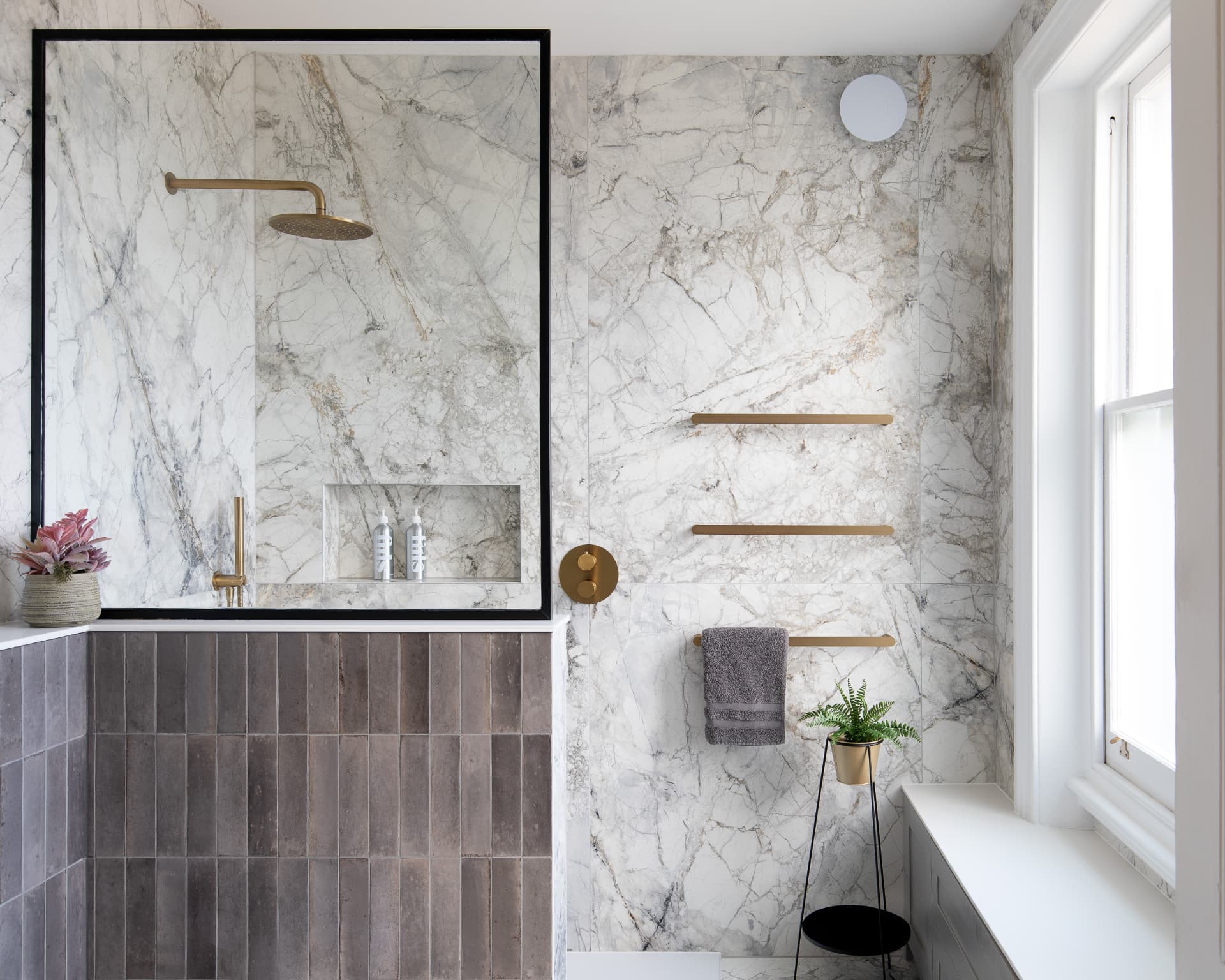 Bathroom in Crystal Palace with walk-in rainfall shower, marble-effect walls, textured grey tiles and brushed brass fittings
